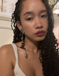 a young woman with curly hair posing for a photo